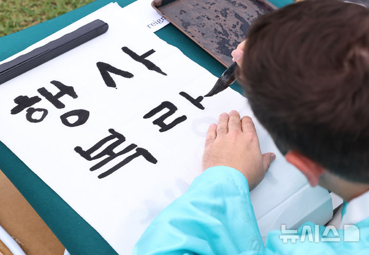[서울=뉴시스] 최진석 기자 = 579돌 한글날인 9일 오전 서울 광화문광장에서 열린 광화문광장 휘호대회에 참가한 외국인이 한글을 쓰고 있다. 2025.10.09. myjs@newsis.com