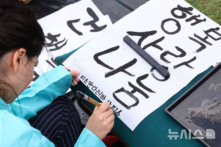 [서울=뉴시스] 최진석 기자 = 579돌 한글날인 9일 오전 서울 광화문광장에서 열린 광화문광장 휘호대회에 참가한 외국인이 한글을 쓰고 있다. 2025.10.09. myjs@newsis.com