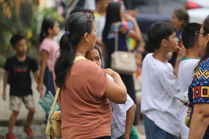 A woman hugs a child as parents and children evacuate a school after a strong earthquake in Davao City, Philippines, on Friday, Oct. 10, 2025. (AP Photo/Manman Dejeto)