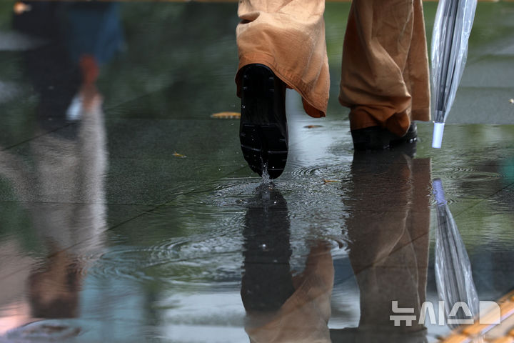 [서울=뉴시스] 조성우 기자 = 비가 내리는 14일 오전 서울 종로구 세종대로 인근에서 인도에 고인 빗물에 이동하는 시민의 모습이 비치고 있다. 2025.10.14. xconfind@newsis.com