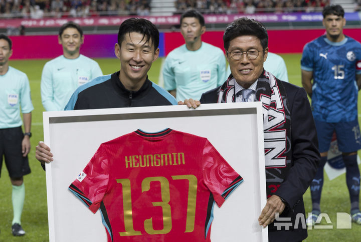[서울=뉴시스] 김근수 기자 = 한국 남자 선수 A매치 최다 출전한 손흥민이 14일 오후 서울 마포구 서울월드컵경기장에서 열린 하나은행 초청 축구국가대표팀 친선경기 대한민국과 파라과이의 경기 시작 전 차범근 전 감독에게 기념 유니폼을 전달받고 기념촬영을 하고 있다.손흥민은 지난 10일 브라질전에 개인 통산 137번째 A매치에 출전했다. 차범근 전 대표팀 감독, 홍명보 대표팀 감독(이상 136경기)을 제치고 한국 남자 축구 역사상 최다 출전 기록 보유자가 됐다. 2010년 12월 시리아전 데뷔 이후 15년 만이다. 2025.10.14. ks@newsis.com