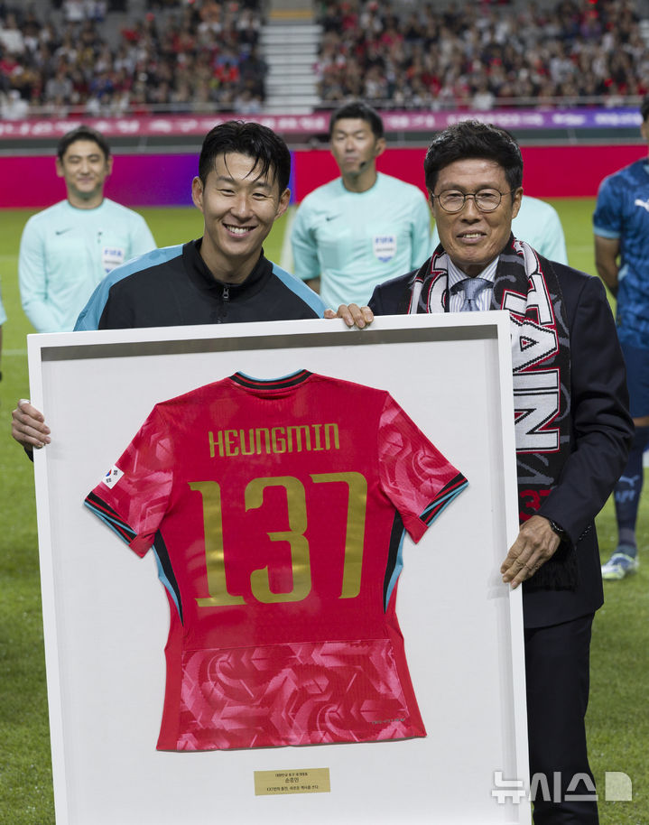 [서울=뉴시스] 김근수 기자 = 한국 남자 선수 A매치 최다 출전한 손흥민이 14일 오후 서울 마포구 서울월드컵경기장에서 열린 하나은행 초청 축구국가대표팀 친선경기 대한민국과 파라과이의 경기 시작 전 차범근 전 감독에게 기념 유니폼을 전달받고 기념촬영을 하고 있다.손흥민은 지난 10일 브라질전에 개인 통산 137번째 A매치에 출전했다. 차범근 전 대표팀 감독, 홍명보 대표팀 감독(이상 136경기)을 제치고 한국 남자 축구 역사상 최다 출전 기록 보유자가 됐다. 2010년 12월 시리아전 데뷔 이후 15년 만이다. 2025.10.14. ks@newsis.com