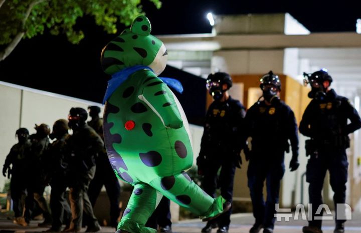 [서울=뉴시스]지난 6일 오후 풍선 개구리 의상을 입은 시위대가 미국 오리건주 포플랜드에 있는 이민세관단속국 본부 밖을 걷고 있다. (사진 = 워싱턴포스트 캡처) imseojin@newsis.com