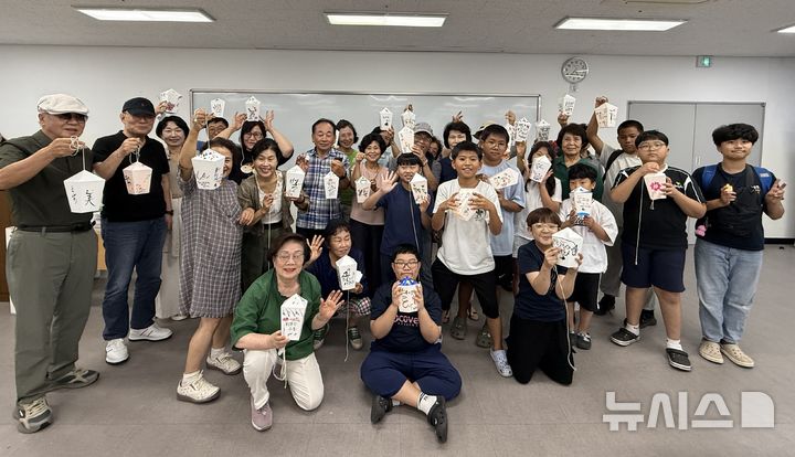 [창원=뉴시스]경남 창원시 마산회원노인종합복지관 '선배시민 금손봉사단'이 지난 8월 27일 초등생 대상 '캘리그라피 무드등 만들기' 재능 기부 활동을 마친 후 기념촬영하고 있다.(사진=마산회원노인종합복지관 제공) 2025.10.15. photo@newsis.com