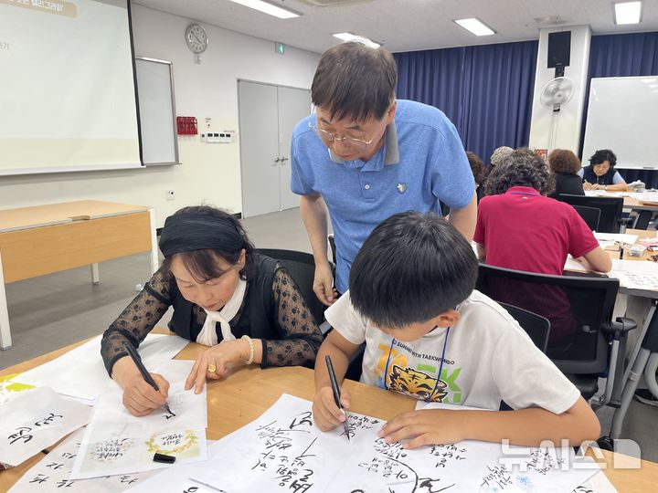 [창원=뉴시스]경남 창원시 마산회원노인종합복지관 '선배시민 금손봉사단' 어르신이 지역 초등생을 대상으로 '캘리그라피'를 지도하고 있다.(사진=마산회원노인종합복지관 제공) 2025.10.15. photo@newsis.com