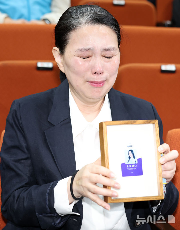 [서울=뉴시스] 이영환 기자 = 고 오요안나씨 어머니 장연미씨가 15일 오전 서울 마포구 MBC에서 열린 고 오요안나 1주기 관련 대국민 기자회견에서 고인의 명예사원증을 들고 있다. 2025.10.15. 20hwan@newsis.com