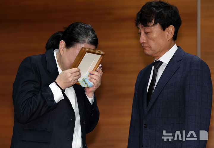 [서울=뉴시스] 이영환 기자 = 고 오요안나씨 어머니 장연미씨가 15일 오전 서울 마포구 MBC에서 열린 고 오요안나 1주기 관련 대국민 기자회견에서 안형준(오른쪽) MBC 사장에게 명예사원증을 전달 받은 후 슬퍼하고 있다. 2025.10.15. 20hwan@newsis.com