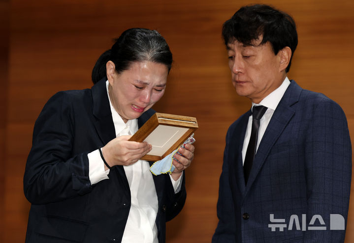 [서울=뉴시스] 이영환 기자 = 고 오요안나씨 어머니 장연미씨가 15일 오전 서울 마포구 MBC에서 열린 고 오요안나 1주기 관련 대국민 기자회견에서 안형준(오른쪽) MBC 사장에게 명예사원증을 전달 받은 후 슬퍼하고 있다. 2025.10.15. 20hwan@newsis.com
