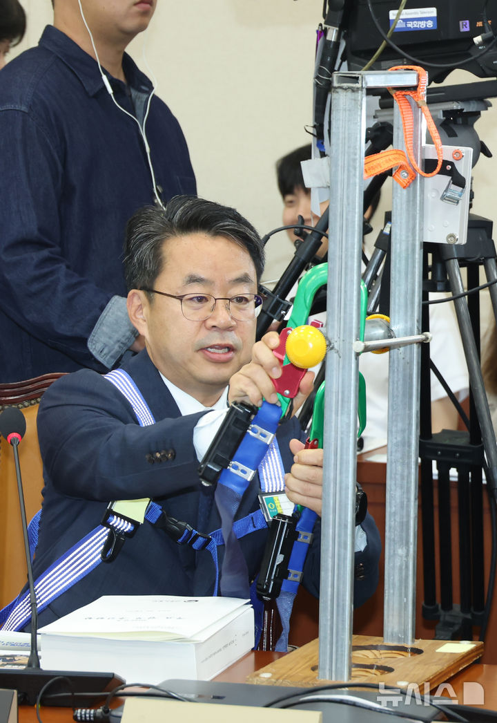 [서울=뉴시스] 고승민 기자 = 박홍배 더불어민주당 의원이 15일 서울 여의도 국회에서 열린 기후에너지환경노동위원회의 고용노동부 등 국정감사에서 하네스 등 산업용 안전장비 관련 질의를 마친 뒤 장비를 거두고 있다. 2025.10.15. kkssmm99@newsis.com