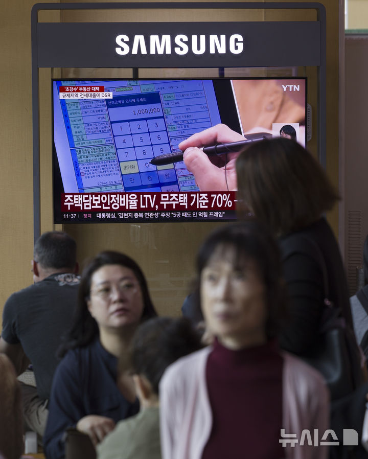 [서울=뉴시스] 김근수 기자 = 정부가 10·15 부동산 대책을 발표한 15일 오전 서울역 대합실 텔레비전에 관련 뉴스가 나오고 있다.정부가 6·27 대출 규제과 9·7공급대책에 이어 발표한 추가 대책은 기존 규제지역인 강남3구·용산구를 포함한 서울 25개 구 전역과 한강 이남의 경기도 12곳 등 총 27곳을 조정대상지역·투기과열지구·토지거래허가구역 등 '삼중 규제지역'으로 묶고 금융규제까지 강화하는 내용이다. 2025.10.15. ks@newsis.com