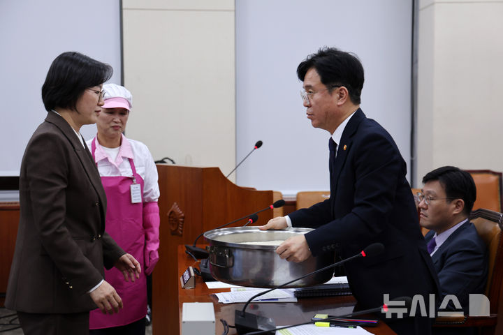 [서울=뉴시스] 김명년 기자 = 김영훈 고용노동부 장관이 5일 서울 여의도 국회 기후에너지환경노동위원회에서 열린 노동부 등에 대한 국정감사에서 정혜경 의원이 준비한 급식노동자 솥을 들어보고 있다. 2025.10.15. kmn@newsis.com