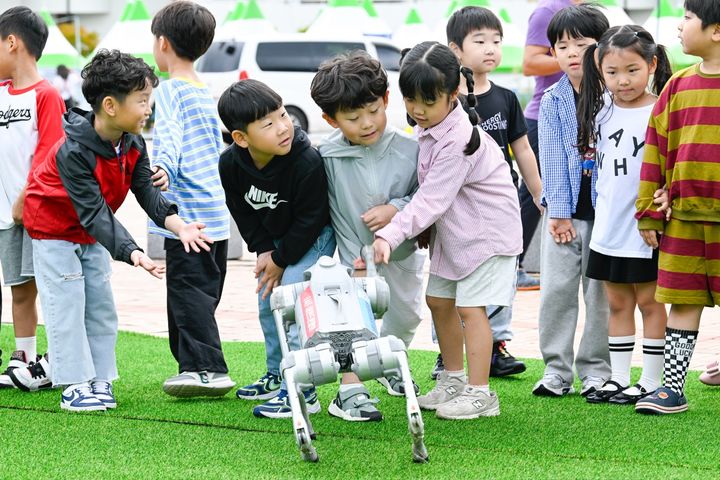[남원=뉴시스] 김종효 기자 = 16일 남원종합스포츠타운에서 열린 '2025 남원국제드론제전 with 로봇', 행사장에 나타난 로봇강아지가 반가운 어린이들이 로봇강아지와 악수하고 있다. (사진=남원시 제공) 2025.10.16. photo@newsis.com *재판매 및 DB 금지