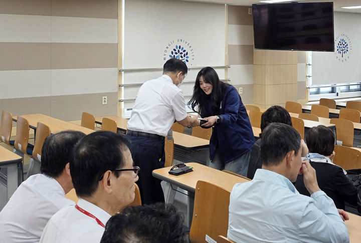 [서울=뉴시스] 명지대 사회봉사단 소속 학생이 교내 경비원에게 손 편지와 선물을 전달하고 있다. (사진=명지대 제공) 2025.10.17. photo@newsis.com *재판매 및 DB 금지