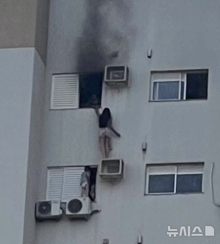[서울=뉴시스]줄리아니 수엘렘 비에이라 도스 레이스(28)가 어머니와 어린 사촌 동생을 구하기 위해 실외기 지지대를 활용해 버티고 있다. (사진=인스타그램 'jeansantos2' 캡처)