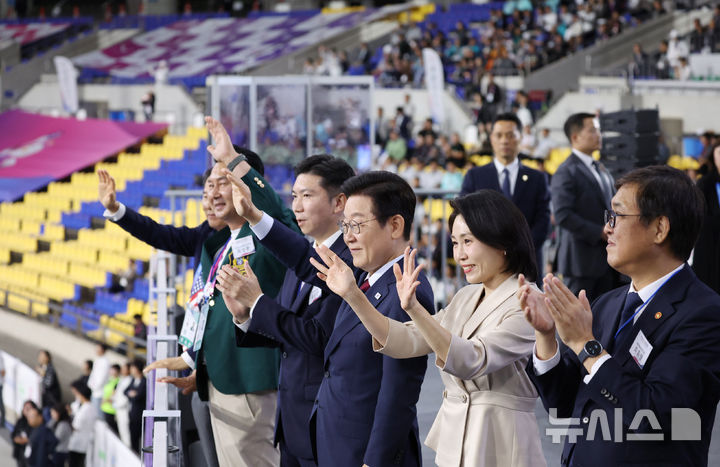 [서울=뉴시스] 최동준 기자 = 이재명 대통령과 김혜경 여사가 17일 부산아시아드주경기장에서 열린 제106회 전국체육대회 개막식에서 선수단 입장을 지켜보며 인사하고 있다. (대통령실통신사진기자단) 2025.10.17. photocdj@newsis.com