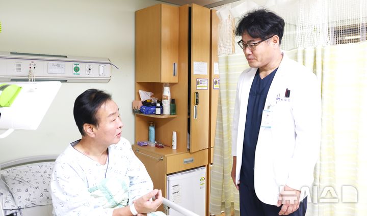[포항=뉴시스] 송종욱 기자 = 포항세명기독병원 지역심뇌혈관질환센터 조재훈 부장(오른쪽)이 뇌경색 진단 후 혈전 제거술을 받고 후유증 없이 회복 중인 A(61)씨를 회진하고 있다. (사진=포항세명기독병원 제공) 2025.10.20. photo@newsis.com