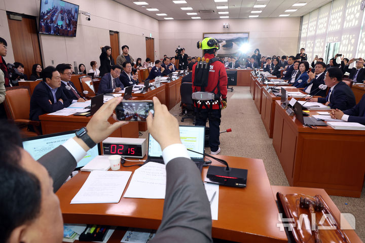 [서울=뉴시스] 고승민 기자 = 문금주 더불어민주당 의원이 20일 서울 여의도 국회에서 열린 농림축산식품 해양수산위원회의 산림청 등 국정감사에서 스마트 웨어러블 장비를 시연하며 질의하고 있다. 어기구 농해수위원장이 이를 촬영하고 있다. 2025.10.20. kkssmm99@newsis.com