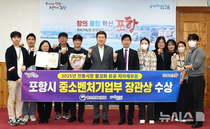 [포항=뉴시스] 송종욱 기자 = 포항시가 중소벤처기업부가 주관한 '2025년 전통 시장 활성화 유공 포상'에서 우수 기관으로 선정돼 중기부 장관 표창장을 받았다. 사진은 21일 시청 대외협력실에서 이강덕 시장과 경제노동정책과 직원들이 수상을 기념해 사진을 찍고 있다. (사진=포항시 제공) 2025.10.21. photo@newsis.com 