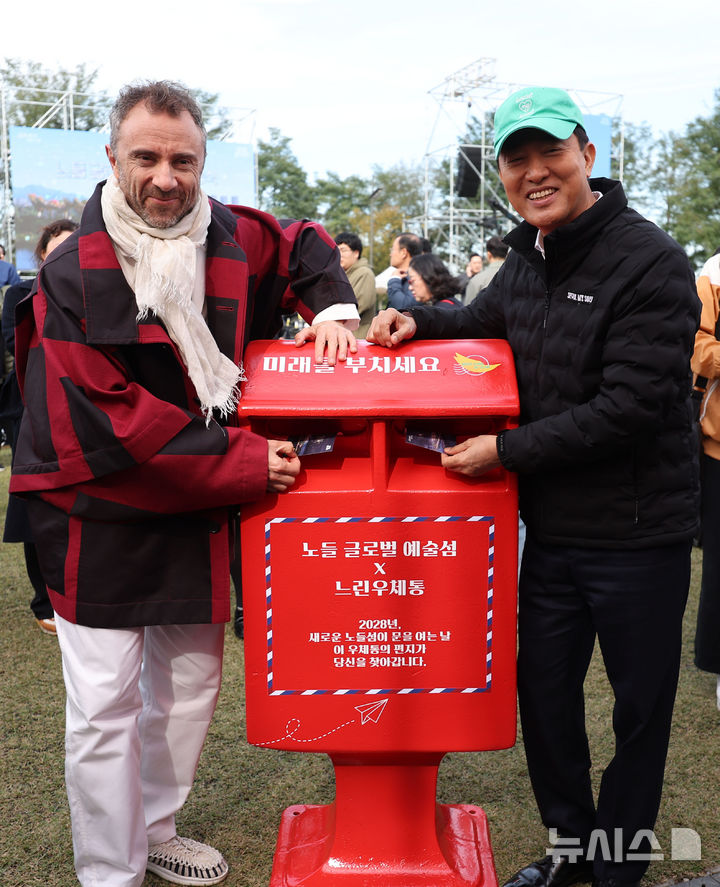 [서울=뉴시스] 김선웅 기자 = 오세훈 서울시장과 건축가 토마스 헤더윅이 21일 서울 용산구 노들섬에서 열린 노들 글로벌 예술섬 착공식을 마친 뒤 완공이 예정된 2028년에 배달될 느린우체통 엽서를 부치고 있다. 2025.10.21. mangusta@newsis.com