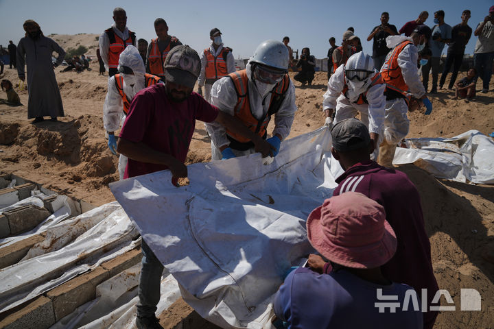 [데이르알발라=AP/뉴시스] 22일(현지 시간) 가자지구 데이르알발라에서 팔레스타인 관계자들이 이스라엘에서 송환된 신원 미상의 팔레스타인인 시신들을 집단 매장하고 있다. 이스라엘은 하마스와 휴전협정에 따라 지금까지 팔레스타인인 시신 150구를 인계한 것으로 알려졌다. 2025.10.23.