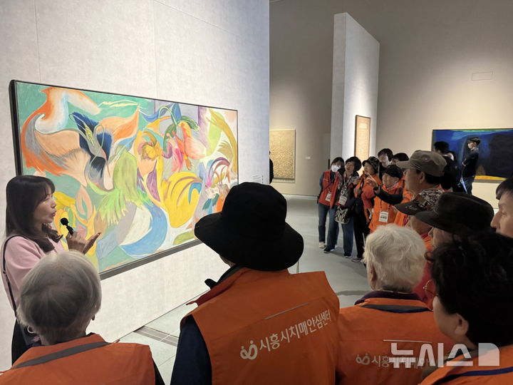 [시흥=뉴시스] 미술관을 방문한 치매 환자와 그 가족이 전문가의 해설에 따라 그림을 감상하고 있다. (사진=시흥시 제공).2025.10.22.photo@newsis.com