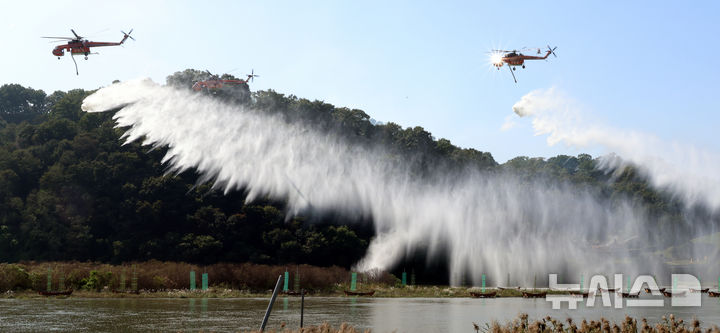 [공주=뉴시스] 강종민 기자 = 22일 충남 공주시 금강변에서 열린 2025 산불진화 통합훈련에서 산불진화헬기들이 방수하고 있다. 2025.10.22. ppkjm@newsis.com