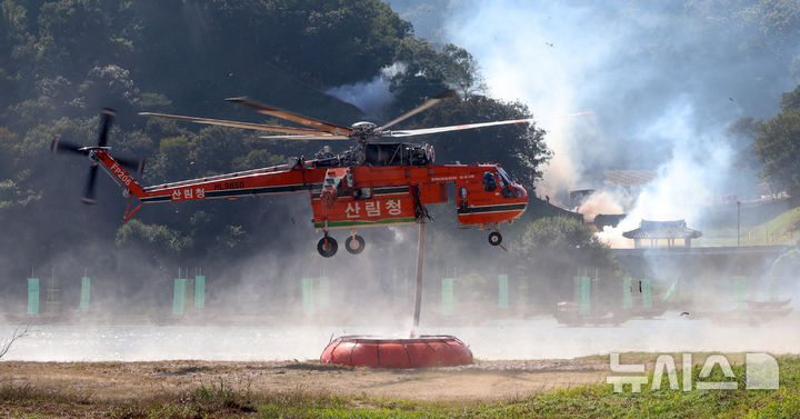 [공주=뉴시스] 강종민 기자 = 22일 충남 공주시 금강변에서 열린 2025 산불진화 통합훈련에서 산불진화헬기가 물을 빨아들이고 있다. 2025.10.22. ppkjm@newsis.com