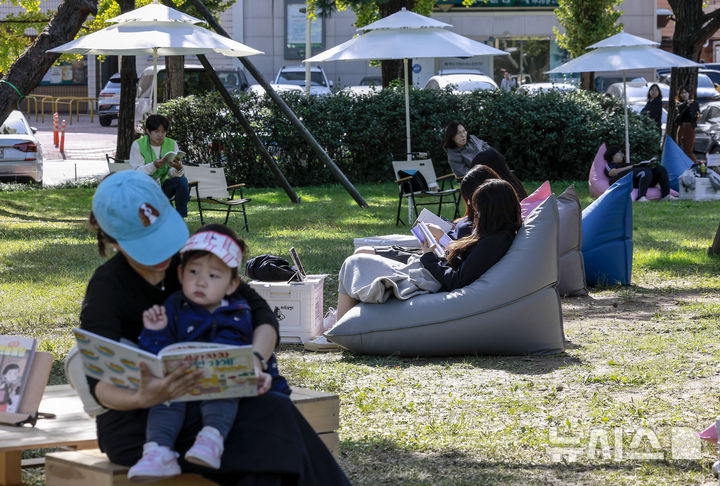 [서울=뉴시스] 정병혁 기자 = 23일 서울 송파구 아시아공원에 마련된 야외도서관을 찾은 시민들이 책을 읽으며 즐거운 시간을 보내고 있다. 송파구청은 가을 독서의 계절을 맞아 동네 공원을 책과 문화가 어우러진 복합문화공간으로 조성해 야외도서관을 운영한다. 2025.10.23 jhope@newsis.com