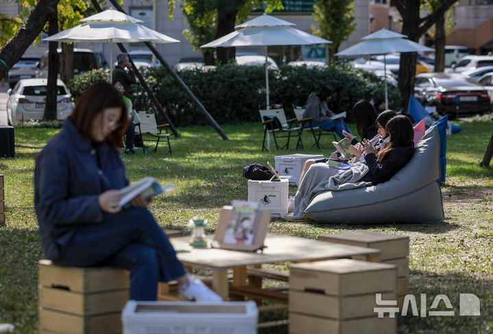 [서울=뉴시스] 정병혁 기자 = 23일 서울 송파구 아시아공원에 마련된 야외도서관을 찾은 시민들이 책을 읽으며 즐거운 시간을 보내고 있다. 송파구청은 가을 독서의 계절을 맞아 동네 공원을 책과 문화가 어우러진 복합문화공간으로 조성해 야외도서관을 운영한다. 2025.10.23 jhope@newsis.com