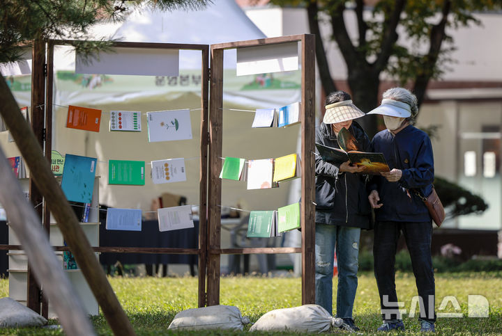 [서울=뉴시스] 정병혁 기자 = 23일 서울 송파구 아시아공원에 마련된 야외도서관을 찾은 시민들이 책을 읽으며 즐거운 시간을 보내고 있다. 송파구청은 가을 독서의 계절을 맞아 동네 공원을 책과 문화가 어우러진 복합문화공간으로 조성해 야외도서관을 운영한다. 2025.10.23 jhope@newsis.com
