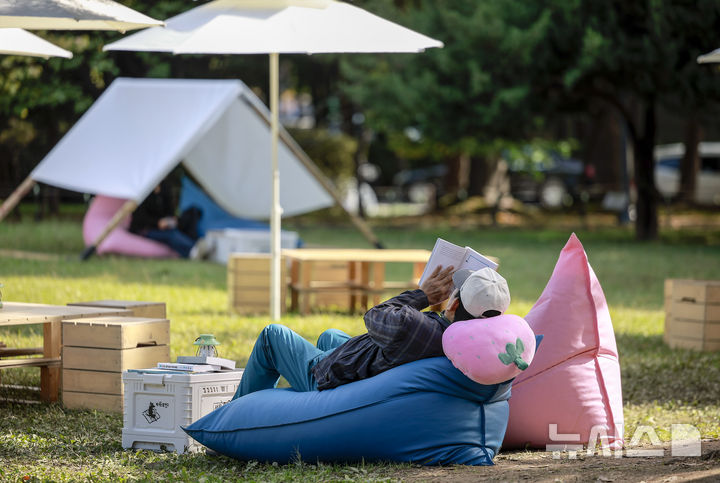 [서울=뉴시스] 정병혁 기자 = 23일 서울 송파구 아시아공원에 마련된 야외도서관을 찾은 시민들이 책을 읽으며 즐거운 시간을 보내고 있다. 송파구청은 가을 독서의 계절을 맞아 동네 공원을 책과 문화가 어우러진 복합문화공간으로 조성해 야외도서관을 운영한다. 2025.10.23 jhope@newsis.com