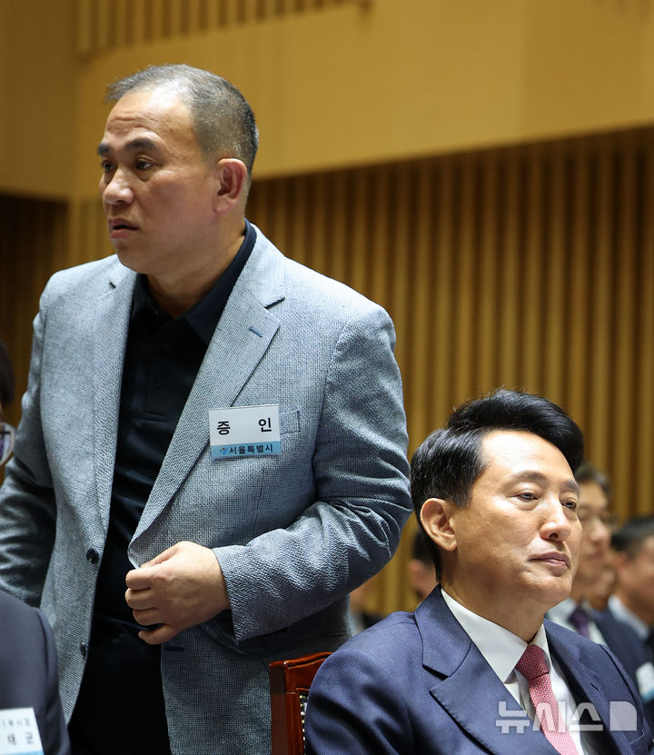 [서울=뉴시스] 김선웅 기자 = '정치브로커'로 알려진 명태균 씨가 23일 서울시청에서 열린 국회 행정안전위원회의 서울특별시에 대한 국정감사에 증인으로 출석해 오세훈 서울시장 뒤를 지나 증언대로 향하고 있다. 2025.10.23. mangusta@newsis.com