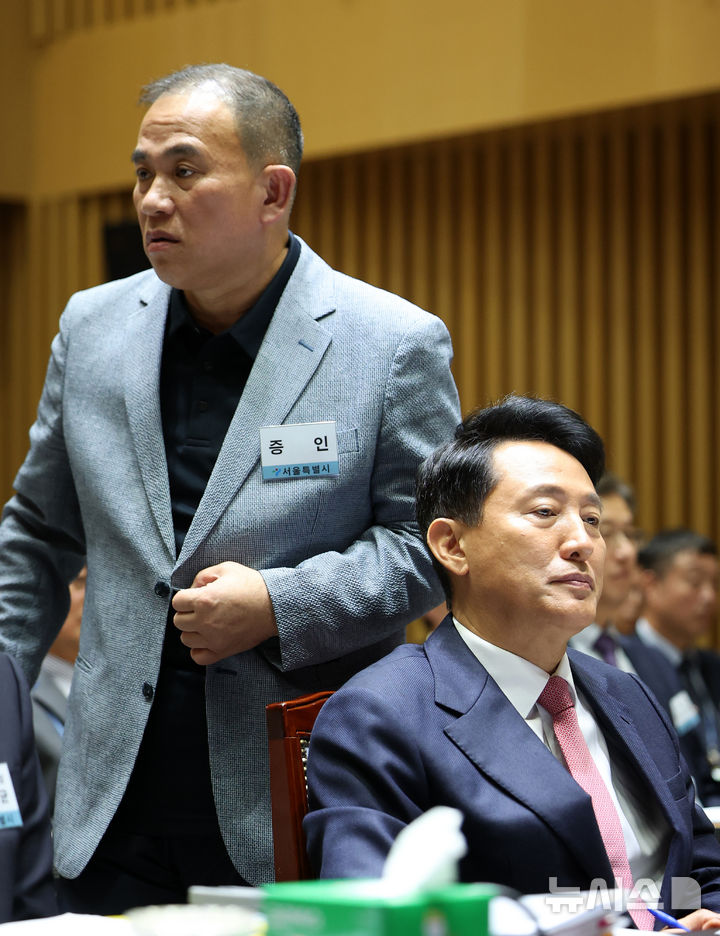 [서울=뉴시스] 김선웅 기자 = '정치브로커'로 알려진 명태균 씨가 23일 서울시청에서 열린 국회 행정안전위원회의 서울특별시에 대한 국정감사에 증인으로 출석해 오세훈 서울시장 뒤를 지나 증언대로 향하고 있다. 2025.10.23. mangusta@newsis.com