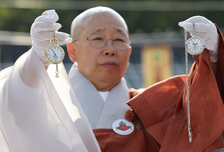 [서울=뉴시스] 전진환 기자 = 광복 80주년을 맞아 진관사 주지 법해스님이 25일 서울 은평구 진관사에서 열린 수륙재 개건 627주년 기념 ‘2025년 진관사 수륙재’ 회향식에서 김진 광복회 부회장에게 받은 김구 선생과 윤봉길 의사가 교환했던 회중시계 복각을 들어보이고 있다. (사진=진관사 제공) 2025.10.26. photo@newsis.com *재판매 및 DB 금지