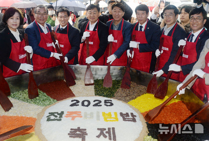 [전주=뉴시스] 김얼 기자 = 김관영(가운데 왼쪽) 전북특별자치도지사와 우범기(가운데 오른쪽) 전주시장을 비롯한 관계자들이 26일 전북 전주시 전주월드컵경기장 특설무대에서 열린 '2025 전주비빔밥축제' 대형 비빔밥 비비기 퍼포먼스에 참석해 비빔밥을 만들고 있다. 2025.10.26. pmkeul@newsis.com