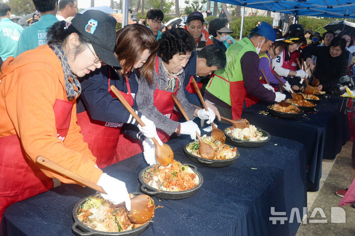 [전주=뉴시스] 김얼 기자 = 2025 전주비빔밥축제 마지막날인 26일 전북 전주시 전주월드컵경기장 특설무대에서 전주비빔밥 만들기에 참가한 시민들이 비빔밥을 비비고 있다. 2025.10.26. pmkeul@newsis.com