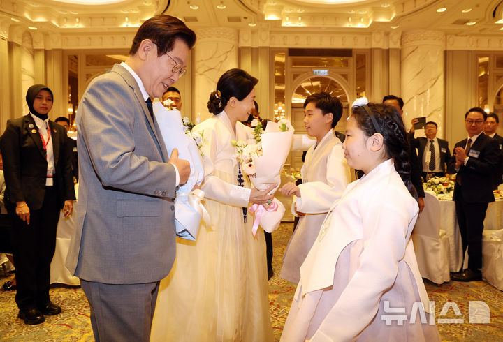 [쿠알라룸푸르=뉴시스] 고범준 기자 = 이재명 대통령과 김혜경 여사가 26일(현지 시간) 말레이시아 쿠알라룸푸르 한 호텔에서 열린 동포 간담회에서 화동에게 꽃다발을 받고 있다. 2025.10.26. bjko@newsis.com