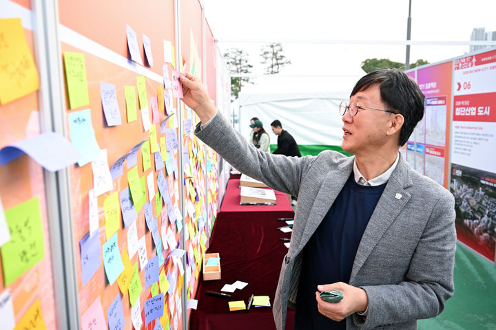 [안산=뉴시스]이민근 안산시장이 26일 '안산페스타 2025' 행사장에 마련된 안산시 홍보관에서 시민들이 안산시에 바라는 의견을 적은 메모지를 살펴보고 있다.(사진=안산시 제공)2025.10.27.photo@newsis.com *재판매 및 DB 금지