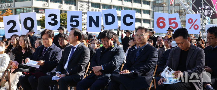 [서울=뉴시스] 박주성 기자 = 지난달 27일 서울 광화문광장에서 김성환 기후에너지환경부 장관(앞줄 오른쪽에서 세번째)이 참석한 제3회 지구하다 페스티벌 개막식에서 기후위기비상행동 회원들이 2035년 국가 온실가스 감축목표(NDC) 65% 수립을 촉구하는 피켓을 들어보이고 있다. 2025.10.27. park7691@newsis.com