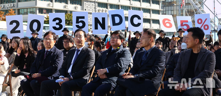 [서울=뉴시스] 박주성 기자 = 지난달 27일 서울 광화문광장에서 김성환 기후에너지환경부 장관(앞줄 오른쪽에서 세번째)이 참석한 제3회 지구하다 페스티벌 개막식에서 기후위기비상행동 회원들이 2035년 국가 온실가스 감축목표(NDC) 65% 수립을 촉구하는 피켓을 들어보이고 있다. 2025.10.27. park7691@newsis.com