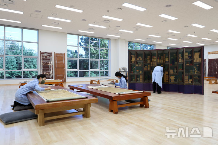 [서울=뉴시스] 박진희 기자 = 국립중앙박물관 보존과학센터 개관식이 열린 28일 보존과학센터 서화실 학예연구사가 조선시대 기록화 '기영회도(耆英會圖)'를 건식 세척 작업을 하고 있다. 2025.10.28. pak7130@newsis.com