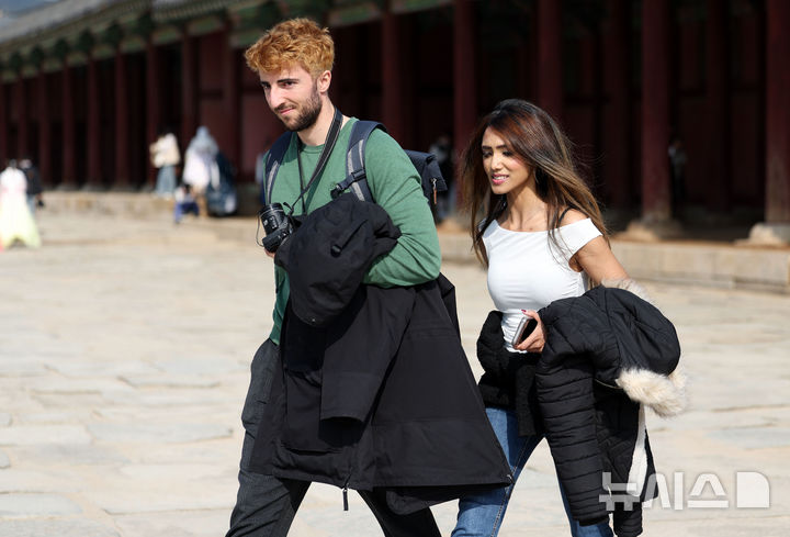 [서울=뉴시스] 홍효식 기자 = 서울 낮 최고기온이 17도까지 오르며 평년 기온을 회복한 29일 오후 서울 종로구 경복궁을 찾은 관람객들이 외투를 벗어 손에 들고 있다. 2025.10.29. yesphoto@newsis.com