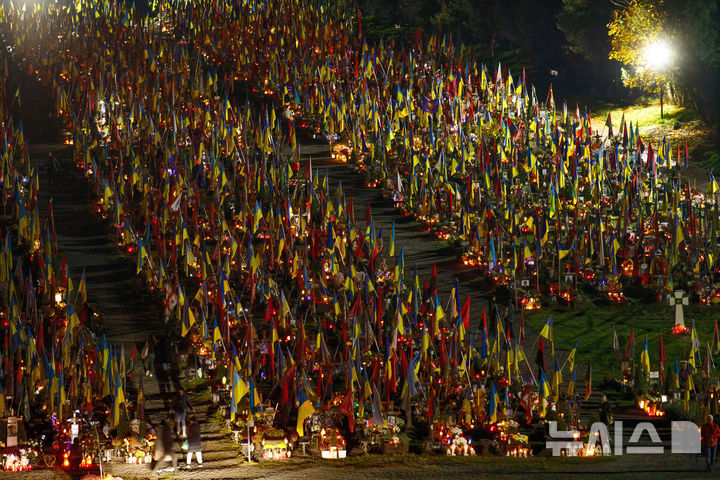 [AP뉴시스] 우크라이나 서부 리비우에서 10월 31일 만성절을 맞아 러시아 침공전 전사자 묘에 가족들이 촛불을 켜고 꽃과 국기를 꽂고 있다