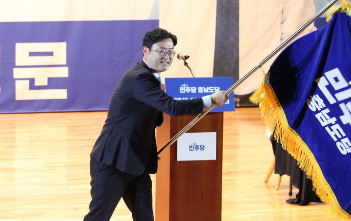 [천안=뉴시스] 최영민 기자=이정문 신임 더불어민주당 충남도당위원장이 1일 충남 천안시 단국대학교 천안캠퍼스에서 열린 임시당원대회에서 위원장에 선출된 후 당기를 흔들고 있다. 2025.11.01 ymchoi@newsis.com *재판매 및 DB 금지