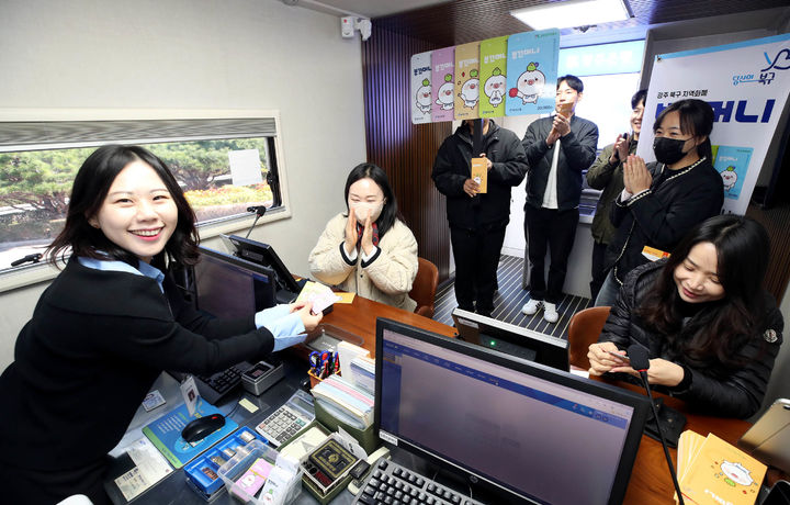 [광주=뉴시스] 광주 북구 지역화폐 '부끄머니' 발행 첫날인 3일 광주 북구청 광장 부끄머니 광주은행 출장버스에서 광주 북구 직원들이 지역 내 소비 활성화와 민생경제 회복을 위해 카드를 발급받고 있다. 부끄머니는 만 14세 이상이면 누구나 북구 소재 광주은행에서 1인당 최대 50만원까지 구매가 가능하며 50만원권을 41만원에 구입할 수 있는 18% 할인 혜택이 적용된다. (사진 = 광주 북구 제공) 2025.11.03. photo@newsis.com *재판매 및 DB 금지