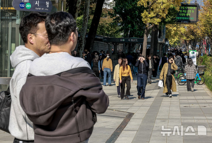 [서울=뉴시스] 정병혁 기자 = 완연한 가을 날씨를 보인 4일 서울 중구 덕수궁 인근에서 겉옷을 벗은 시민이 신호를 기다리고 있다. 2025.11.04. jhope@newsis.com