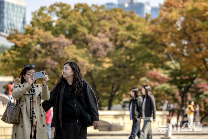 [서울=뉴시스] 정병혁 기자 = 완연한 가을 날씨를 보인 4일 서울 중구 덕수궁을 찾은 여행객이 사진을 찍고 있다. 2025.11.04. jhope@newsis.com