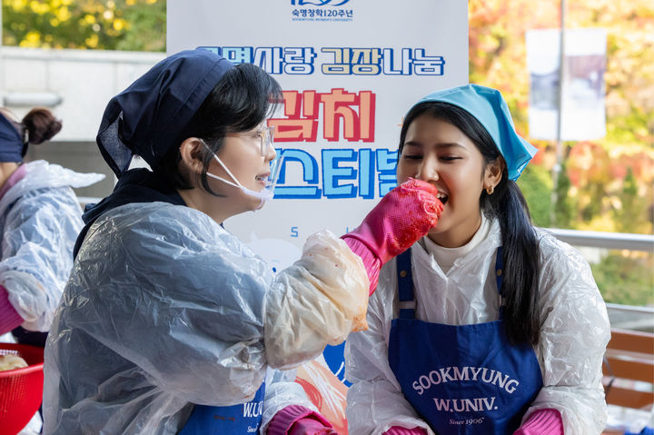 [서울=뉴시스] 지난 4일 열린 '김치 페스티벌-숙명사랑 김장나눔 봉사'에서 문시연 숙명여대 총장(왼쪽)이 한 외국 학생에게 직접 김치를 먹여주고 있다. (사진=숙명여대 제공) 2025.11.05. photo@newsis.com *재판매 및 DB 금지