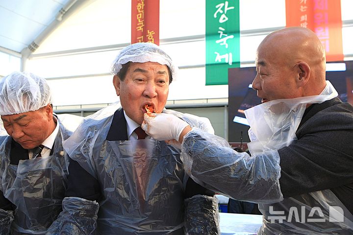 [평창=뉴시스] 이덕화 기자 = 5일 강원 평창군 대표 미식축제인 제8회 평창고랭지김장축제가 개막한 가운데 심재국 군수가 장문혁 축제위원장이 건네는 김치를 받아 먹고 있다. 2025.11.05. wonder8768@newsis.com