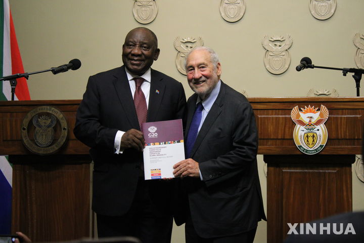 [케이프타운=신화/뉴시스] 시릴 라마포사 남아프리카공화국 대통령(왼쪽)이 4일(현지 시간) 남아공 케이프타운에서 열린 기념식에서 노벨상 수상자인 조지프 스티글리츠 미 컬럼비아대 교수로부터 주요20개국(G20) 글로벌 불평등 특별위원회 보고서를 건네받고 있다. 특위는 세계 불평등이 비상사태에 직면해 있다며 글로벌 차원의 정책 결정을 이끌 국제위원회 창설을 제안했다. 2025.11.05.